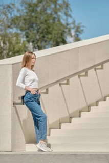 Woman standing on stairs in profile with her hands in pockets