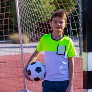 Symbolic image: Ten-year-old boy on a football pitch proudly holding a football in his arms