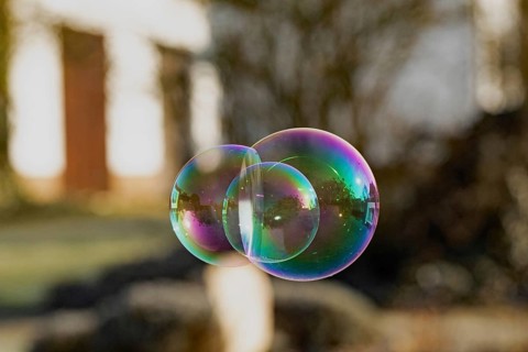 Soap bubbles three-coloured film of soapy water next to each other with mirror image in front of
