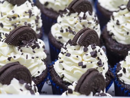 Close-up of a large group chocolate cupcakes with white cream frosting and dark chocolate cookie