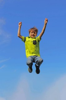 Symbolic image: Boy jumping into the air, blue sky in the background