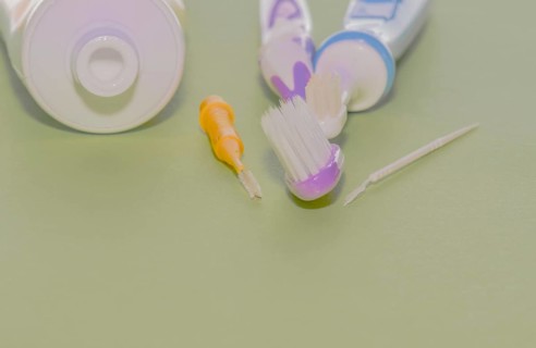 Closeup of toothbrushes and flossing picks next to opened tube of toothpaste