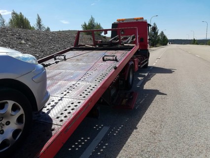 Detail of a tow truck towing a damaged car in the middle of the street