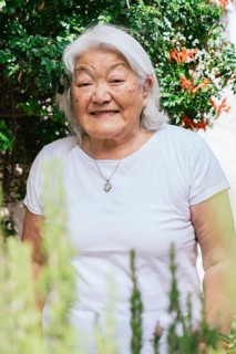 Portrait of a white-haired elderly woman of Japanese ethnicity smiling and looking at the camera in
