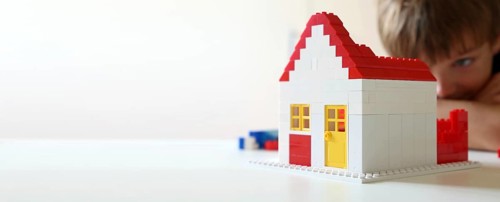 Boy builds a house with building blocks (with free space for text)