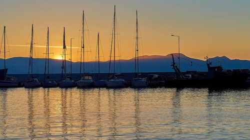 Yachts in the harbour at sunset with mountains in the background and evening sky, Gythio, Mani,