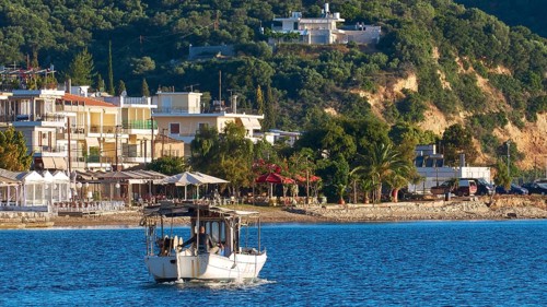 Fishing boat on an idyllic Mediterranean coast with town and hills in the background, Gythio, Mani,
