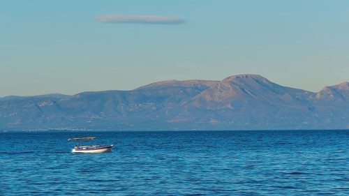 Lonely boat on the wide blue sea with mountains in the background and clear sky, Gythio, Mani,