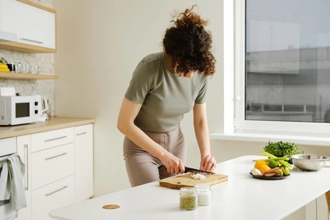 Young woman cutting shallot onion in the kitchen