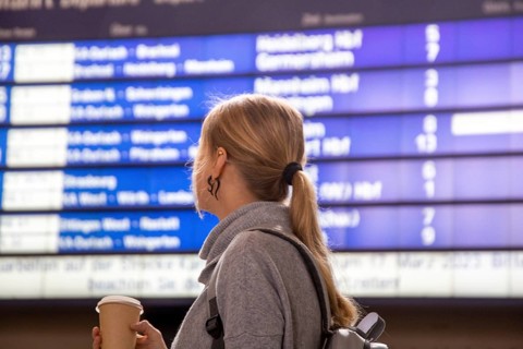 Young woman looking at the scoreboard in a railway station