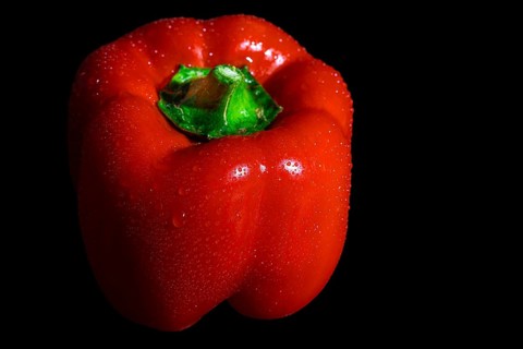 Red capsicum with drops on the surface, dark background