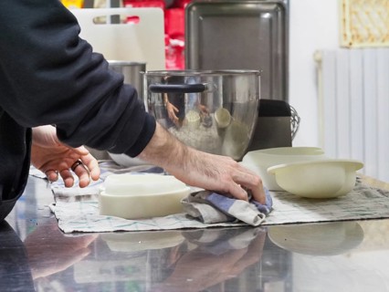 Person cleaning a countertop next to bowls and a blender in a kitchen environment