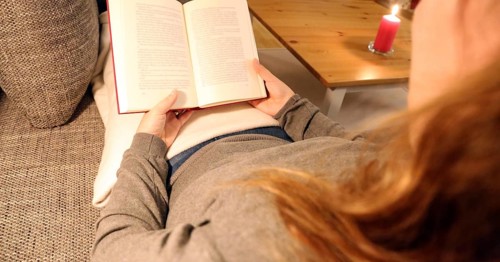 Woman comfortably reading a book on the sofa