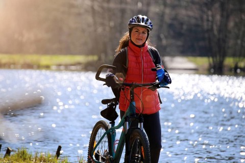 Attractive mountain biker stands with her mountain bike in front of a lake