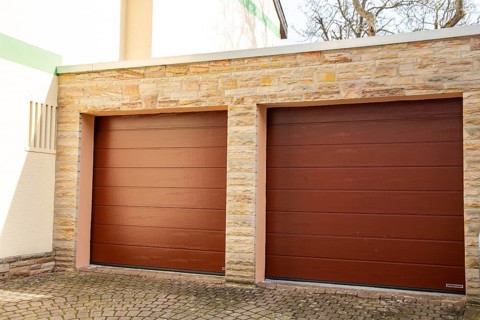 Two red sectional doors from the manufacturer Hoermann on the garage of a detached house
