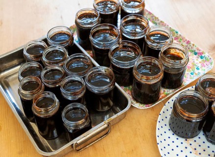 Open topped jam jars filled with setting dark liquid quince jam jelly homemade conserve