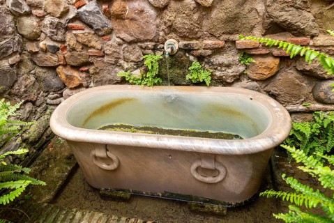 Stone water fountain bath in garden of historic Moorish palace Alcazaba, Malaga, Andalusia, Spain,