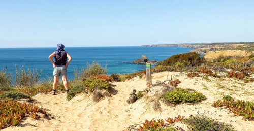 One woman walking on cliffs above the Atlantic Ocean on coastal long distance footpath trail, The