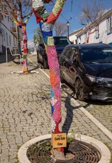 Star shaped wool crochet woollen pattern around tree trunk in street of village Mertola, Portugal,