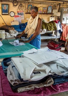 A man irons shirts with an antique iron at Dhobi Khana Public Laundry, Fort Kochi, Cochin, Kerala,