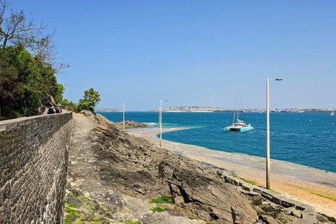 Fortified coast with catamaran in front of rocky shore in Dinard, Ille-et-Vilaine, Brittany,
