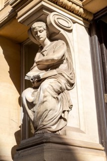 Victorian sculpture of woman reading a book outside old library building in city centre, Cardiff,