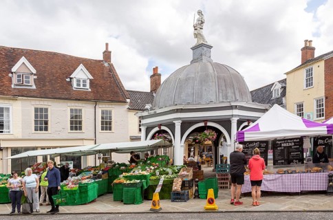 People shopping at market stalls by the Buttercross, Bungay, Suffolk, England, UK