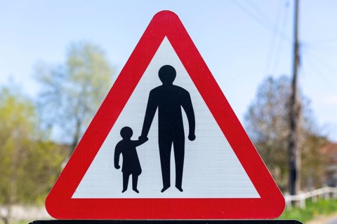 Macro close up Highway Code red triangle road sign warning of pedestrians walking, UK