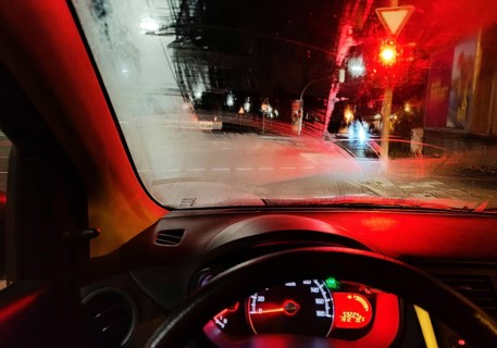 View from the car in dangerously poor visibility at night with rain in front of a red traffic
