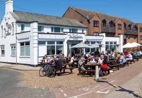 People sitting in sunshine outside the Jolly Sailors pub, Pakefield, Lowestoft, Suffolk, England,