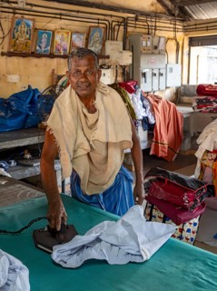 A man irons shirts with an antique iron at Dhobi Khana Public Laundry, Fort Kochi, Cochin, Kerala,