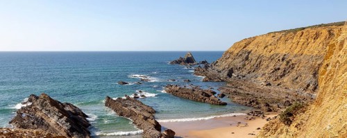 Rocky coastal landscape Praia dos Alteirinhos beach in bay with rocky headland part of Parque