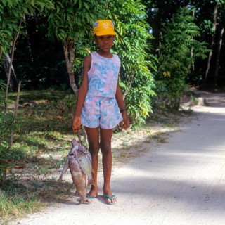 Girl carrying fish on the island of La Digue, Seychelles, Africa