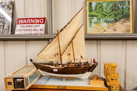 Model sailing ship and other items on display inside an auction room