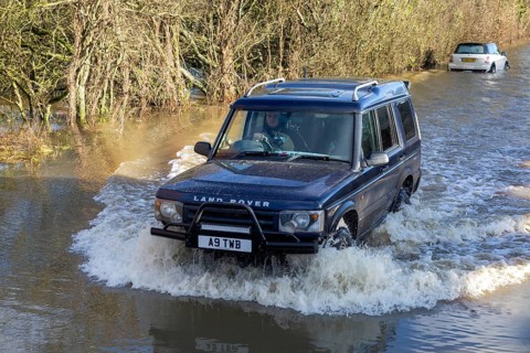 Land Rover Discovery Td5 vehicle driving through flood water at Kellaways, Wiltshire, England, UK