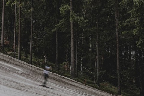 A skier skis on an artificially snow-covered and dirty slope, taken on a ski slope in the Jizera