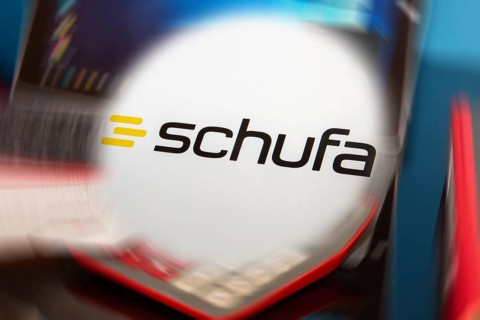 Symbolic image Schufa (information) : Schufa logo in front of a desk with tablet, calculator and