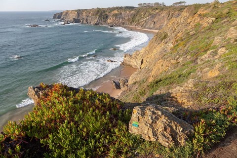 Secluded sandy beach in bay between rocky headlands at Parque Natural do Sudoeste Alentejano e