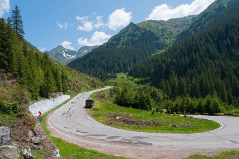 Camper on a winding mountain road, surrounded by forest and snow, mountain road, Transfogarasan