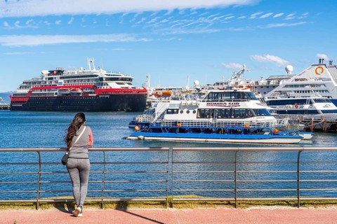 A woman watches cruise ships in the harbour on the Beagle Channel, Ushuaia, Tierra del Fuego
