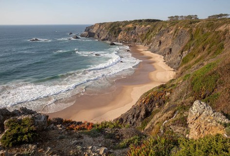 Secluded sandy beach in bay between rocky headlands at Parque Natural do Sudoeste Alentejano e