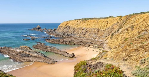 Sandy beach Praia dos Alteirinhos, Zambujeira do Mar in bay between rocky headlands part of Parque