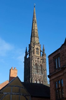 Steeple spire of old cathedral rising above historic buildings, Coventry, West Midlands, England,