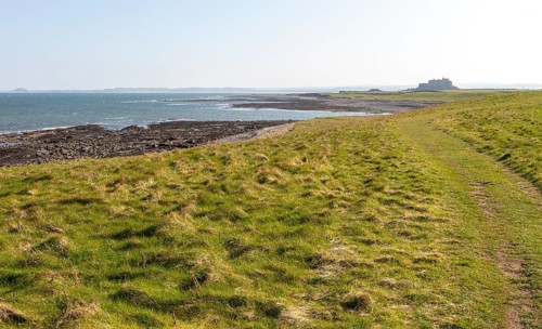 Coastline landscape scenery looking south towards Farne Islands and castle, Holy Island,