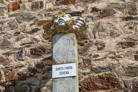 Ancient marble sculpture of Saint Mary, Santa Maria, aged with orange shield lichen resting one