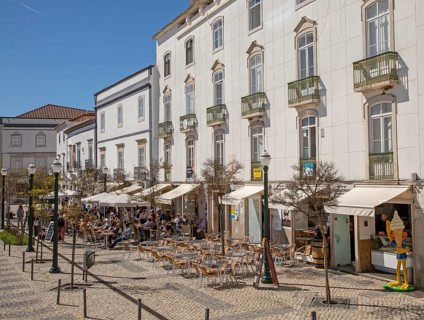 People sitting in sunshine outside street cafes in Praca da Republica, Tavira, Algarve, Portugal,