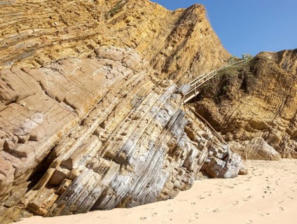 Folded sedimentary rock strata dipping downwards in cliff at Praia dos Alteirinhos, Zambujeira do