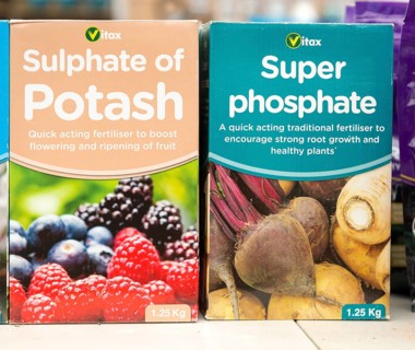 Cardboard boxes of Vitax Sulphate of Potash and Super Phosphate on shelf display in garden centre,