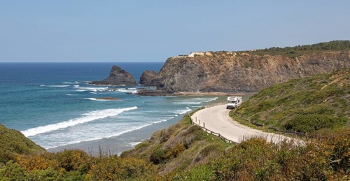 Motorhome parked at viewpoint of Atlantic Ocean waves breaking on rocky headland and bay with sandy