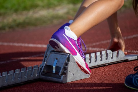 Young track and field athlete with Cougar spikes at the starting block in front of a sprint